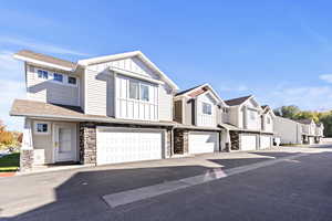 Craftsman house with board and batten siding, an attached garage, a residential view, stone siding, and roof with shingles