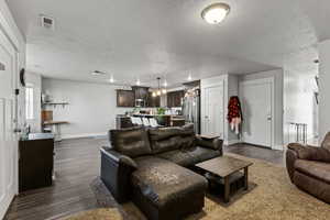 Living area featuring dark wood-type flooring and a textured ceiling