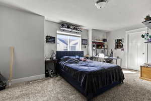 Carpeted bedroom with a textured ceiling and baseboards