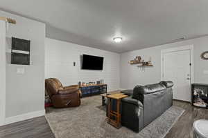 Living room featuring a textured ceiling, dark wood-type flooring, and wood walls