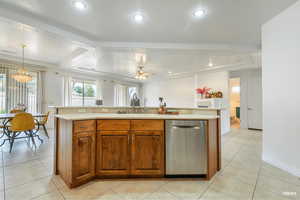 Kitchen with a kitchen island with sink, stainless steel dishwasher, brown cabinetry, and light countertops
