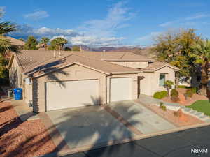 View of front of property featuring a garage, stucco siding, concrete driveway, and a mountain view