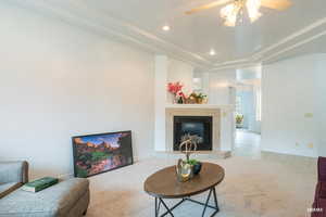 Living area with a tile fireplace, ceiling fan, recessed lighting, a raised ceiling, and tile patterned floors