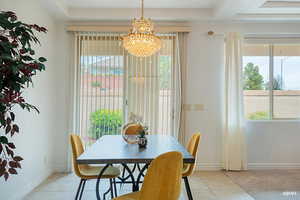 Dining room with a chandelier, light tile patterned floors, and healthy amount of natural light