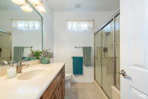 Full bathroom featuring vanity, light tile patterned flooring, and a shower stall
