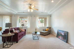 Carpeted living room with a tray ceiling, a textured ceiling, and ceiling fan