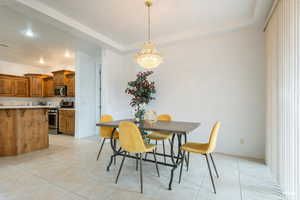 Dining space with light tile patterned floors, recessed lighting, a chandelier, and a tray ceiling