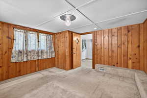 Carpeted spare room with wood walls