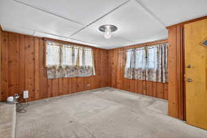 Carpeted spare room with plenty of natural light and wooden walls