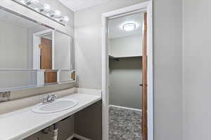 Bathroom featuring vanity, a walk in closet, and a textured ceiling