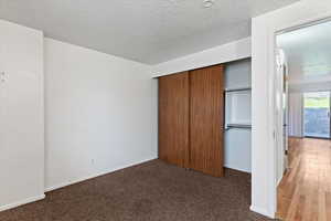 Unfurnished bedroom featuring a closet, a textured ceiling, and carpet floors