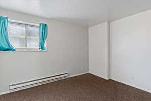Unfurnished room with a baseboard heating unit, carpet, and a textured ceiling