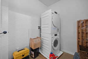 Laundry area featuring estacked washer and dryer and wood finished floors
