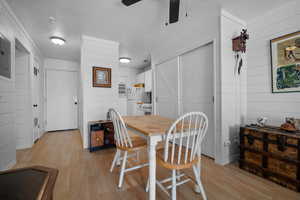 Dining space featuring wood walls, light wood finished floors, electric panel, and ceiling fan