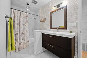 Full bath with shower / tub combo, vanity, light marble finish floors, and a chandelier