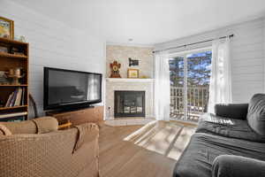 Living room featuring wood walls, a large fireplace, and wood finished floors