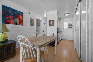 Dining space with light wood-type flooring, electric panel, and wooden walls