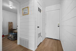 Hall with light wood finished floors and wooden walls