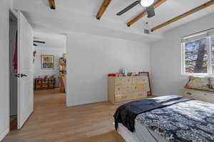 Bedroom with light wood-style flooring, beam ceiling, and a ceiling fan
