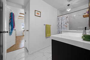Bathroom with light marble finish flooring, vanity, a shower with curtain, and a chandelier