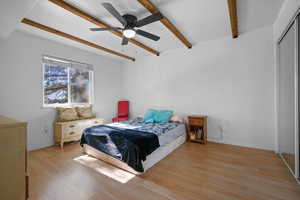 Bedroom with beamed ceiling, light wood-style floors, a ceiling fan, and a closet