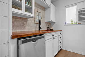 Kitchen featuring wooden counters, white cabinets, dishwasher, glass insert cabinets, and light wood finished floors