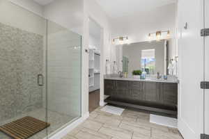 Bathroom with a shower stall, double vanity, and a walk in closet