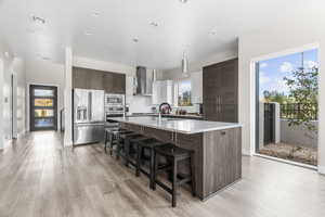 Kitchen featuring dark brown cabinets, healthy amount of natural light, stainless steel appliances, a breakfast bar area, and recessed lighting