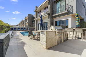 Patio / terrace with a patio area, a community pool, and exterior kitchen