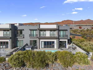 Rear view of property featuring a patio area, a balcony, stucco siding, stone siding, and a mountain view