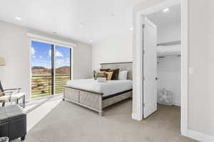 Bedroom featuring light colored carpet, a spacious closet, access to exterior, a mountain view, and recessed lighting