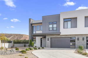 Contemporary home featuring stucco siding, a mountain view, concrete driveway, a garage, and stone siding