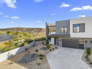 Contemporary house featuring stone siding, a standing seam roof, and stucco siding