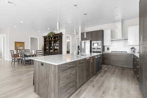 Kitchen with white cabinetry, modern cabinets, dark brown cabinets, decorative backsplash, and a large island with sink