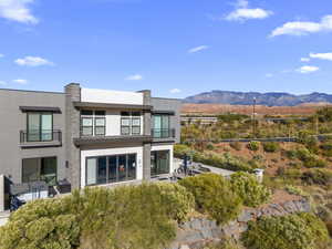 Back of house featuring a balcony, a standing seam roof, a metal roof, and stucco siding