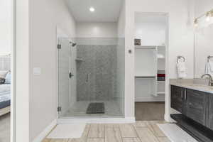 Ensuite bathroom featuring a walk in closet, vanity, a shower stall, and recessed lighting