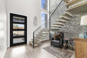 Entrance foyer featuring healthy amount of natural light, a towering ceiling, light wood finished floors, and stairway
