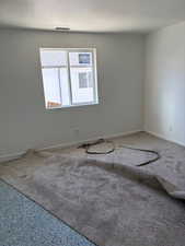 Carpeted empty room featuring a textured ceiling and baseboards
