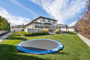 Back of property featuring a trampoline, stucco siding, and a patio area