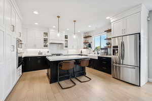Kitchen featuring dark cabinetry, stainless steel appliances, a breakfast bar area, backsplash, and open shelves