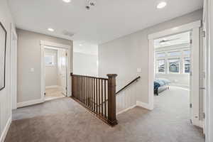 Hallway with an upstairs landing, carpet flooring, and recessed lighting