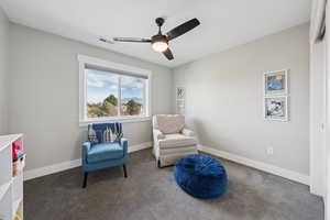 Living area featuring dark carpet and a ceiling fan