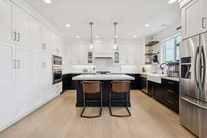 Kitchen featuring dark cabinets, appliances with stainless steel finishes, white cabinets, backsplash, and open shelves