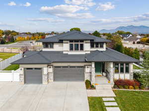 Prairie-style home with concrete driveway, stucco siding, stone siding, a garage, and a residential view