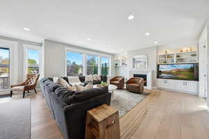 Living area featuring light wood-style flooring, plenty of natural light, built in shelves, and recessed lighting