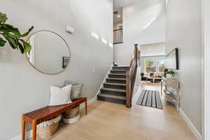 Stairway with a towering ceiling, wood finished floors, and recessed lighting