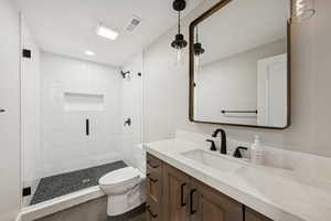 Bathroom with a stall shower, dark tile patterned flooring, and vanity