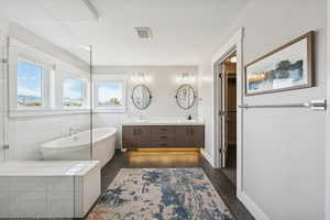 Full bathroom featuring a freestanding tub, double vanity, and a spacious closet