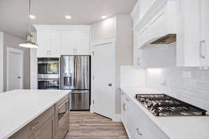Kitchen featuring hanging light fixtures, appliances with stainless steel finishes, white cabinetry, and recessed lighting
