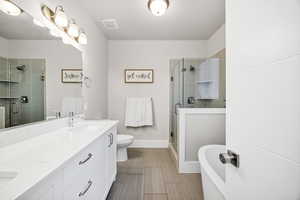 Bathroom with double vanity, a stall shower, a freestanding tub, and wood tiled floors